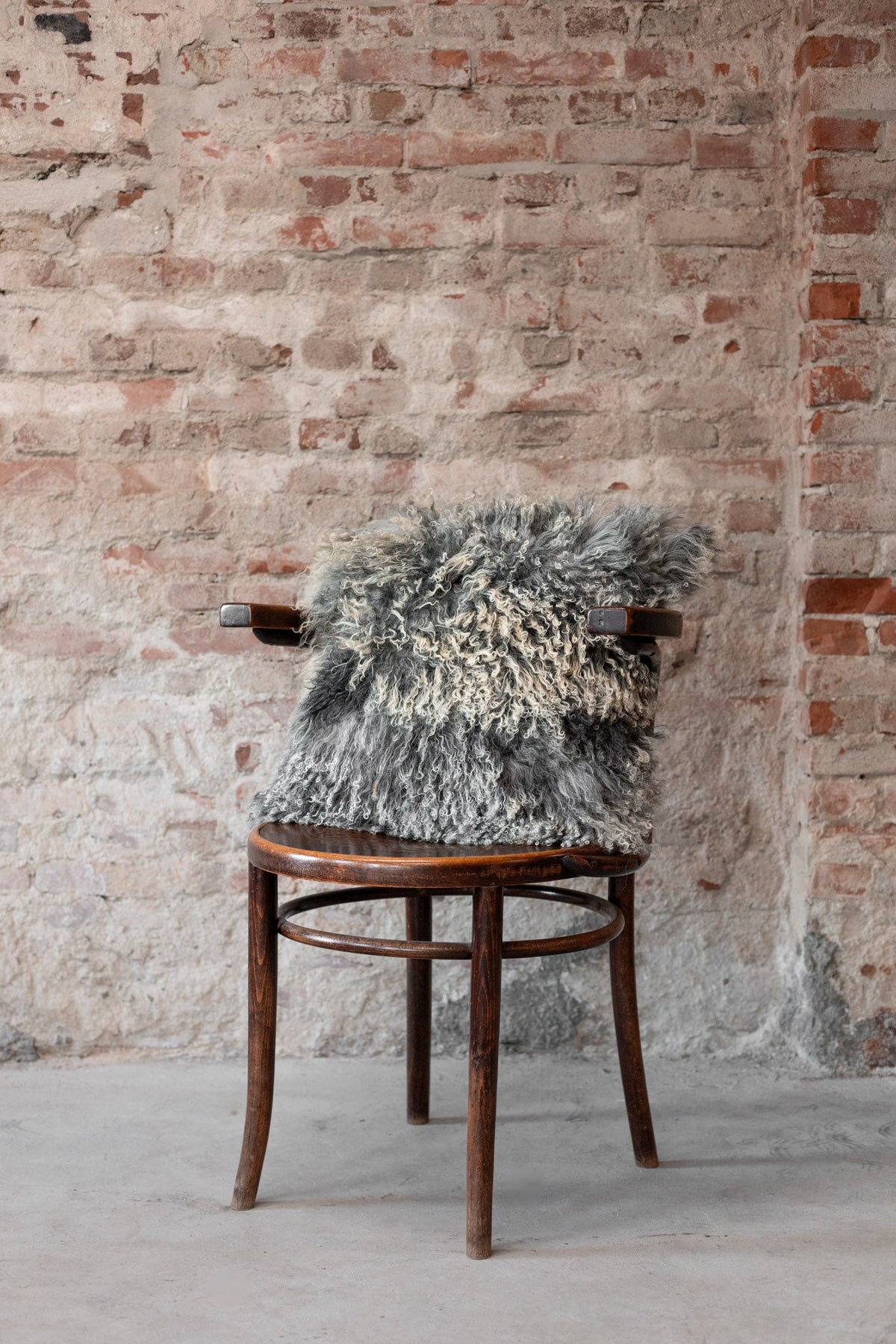 Housse garnie en peau de mouton du Tibet gris naturel posée sur une chaise en bois
