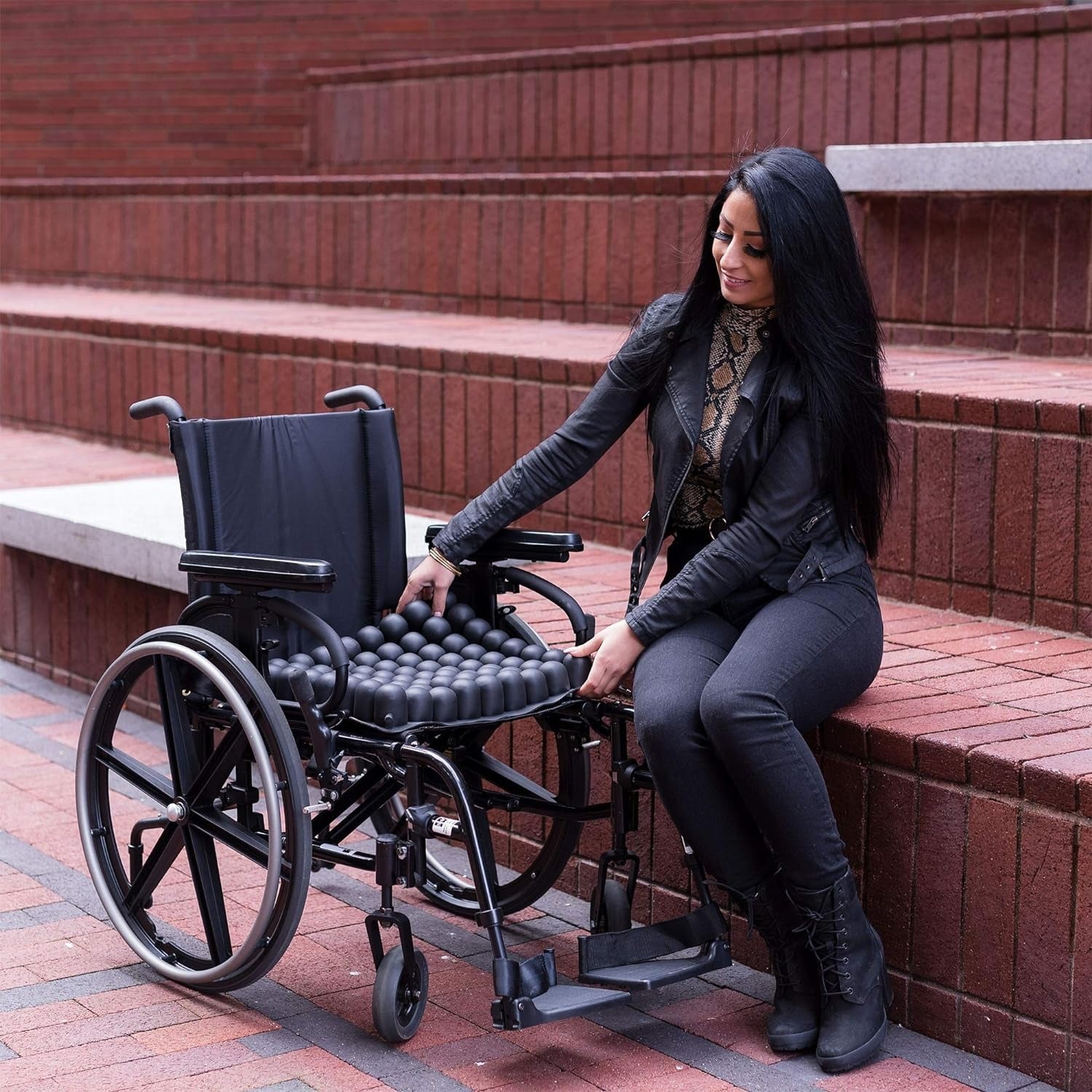 Femme en train de positionner un coussin anti escarre sur un fauteuil roulant