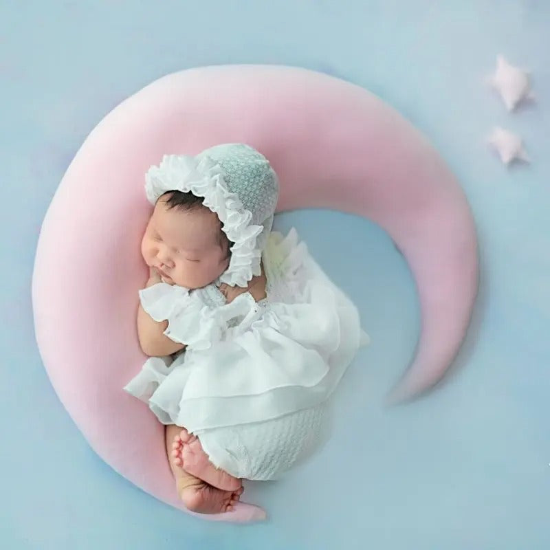 Coussin bébé naissance en forme de lune avec un bébé qui dort le tout sur un fond bleu