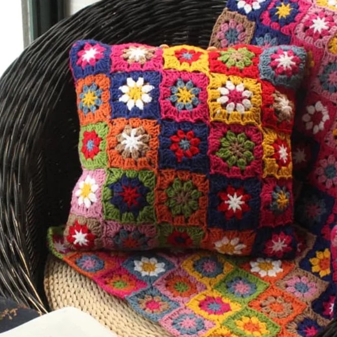 Coussin au crochet multicolore avec motifs de fleurs brodés sur une chaise en bois