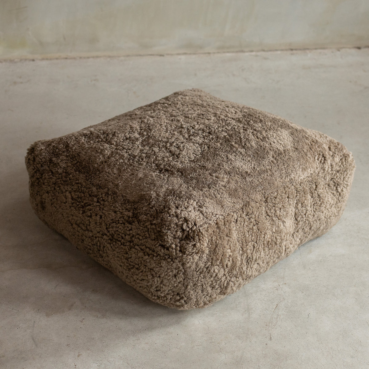 Coussin de sol peau de mouton bouclée sahara vu de trois quarts, boucles naturelles denses