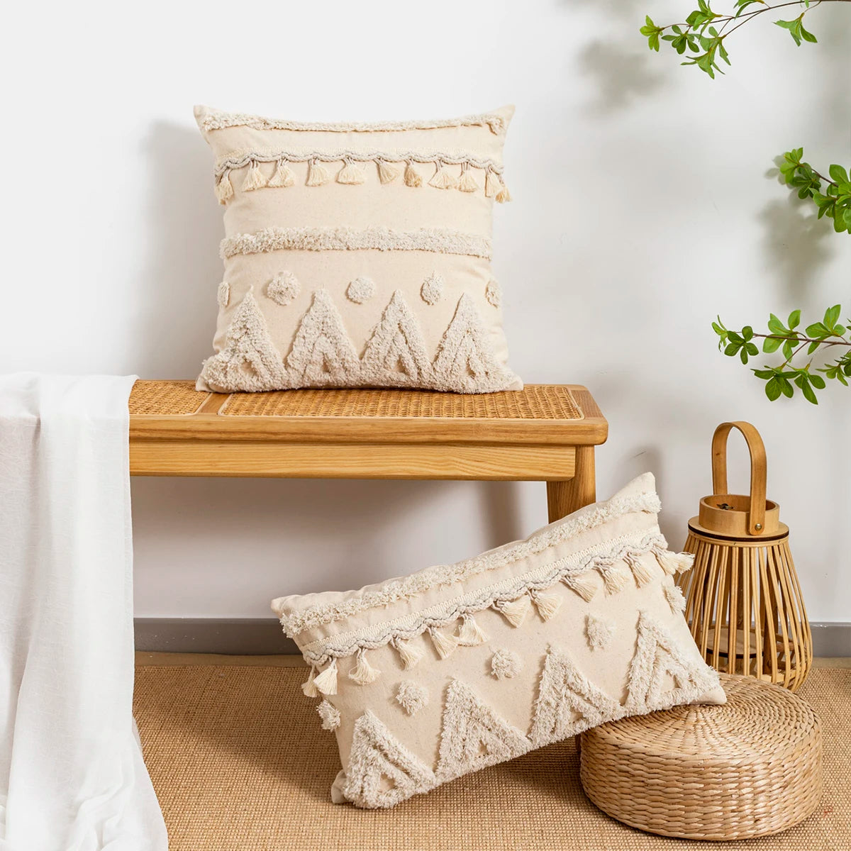 Coussin brodé marocain beige à pampilles sur fond blanc avec une table en bois