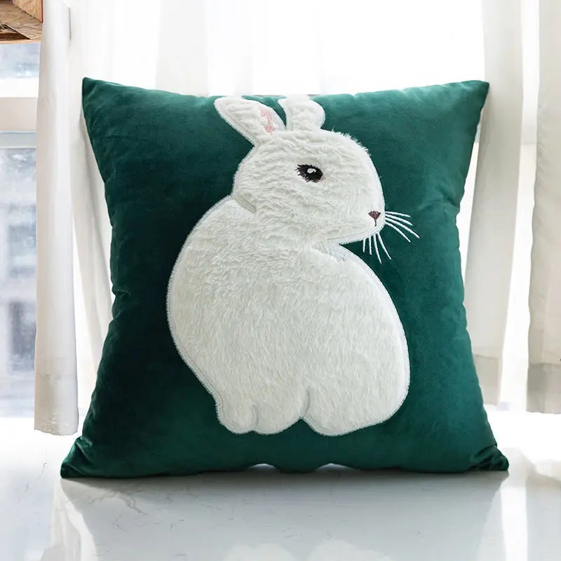 Coussin déco animaux vert avec lapin blanc sur fond de rideaux blancs