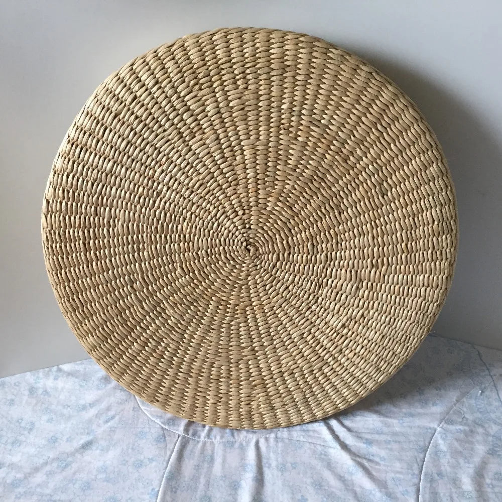 Coussin sol rond en paille naturelle sur un lit sur fond gris