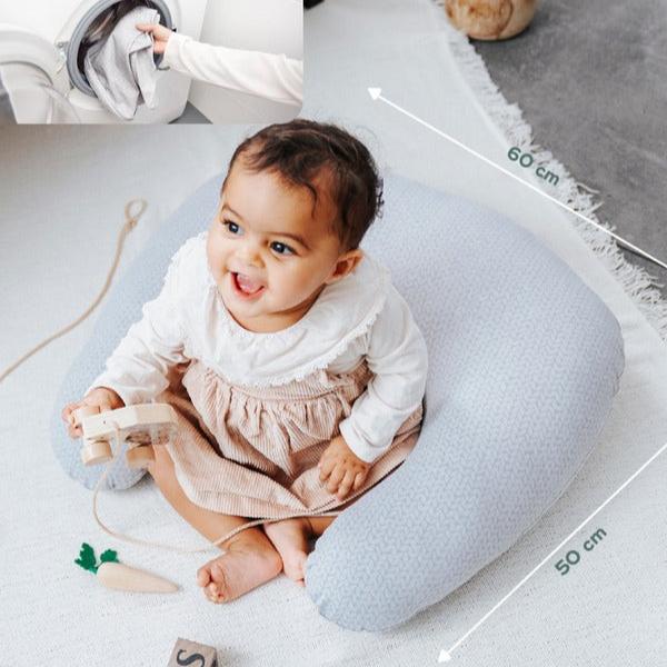 Petit coussin d'allaitement avec un bébé et une image qui montre qu'il peut être lavé en machine